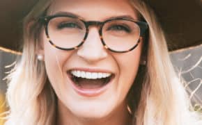 Frau mit Brille und Hut lacht