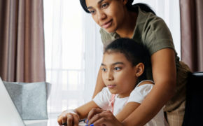 Eine Mutter zeigt ihrer Tochter etwas auf ihrem Laptop.