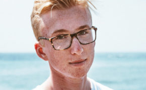 Junge mit Brille steht am Strand