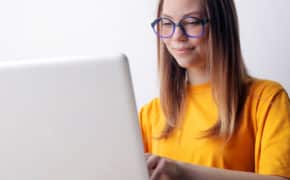 Frau mit Brille sitzt am Laptop