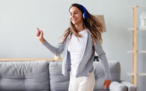 Frau mit Kopfhörern tanzt im Wohnzimmer.
