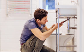 Mann kniet im Badezimmer und repariert Waschbecken