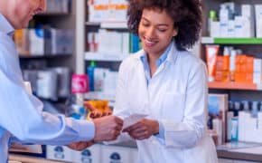 Apothekerin bedient einen Kunden an der Theke