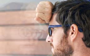 Mann mit Brille lehnt sich gegen ein Fenster.
