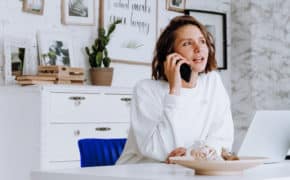 Frau sitzt vor ihrem Laptop und telefoniert mit kritischem Blick.