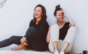 Zwei Frauen sitzen auf dem Boden und lachen