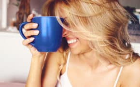 Frau mit Tasse im Gesicht lacht