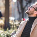 Mann sitzt auf Bank und genießt die Sonne