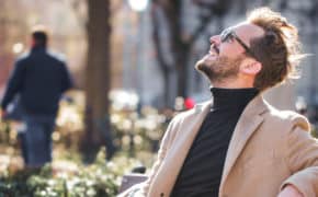 Mann sitzt auf Bank und genießt die Sonne