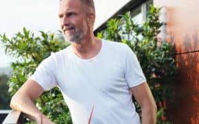 Ein Mann steht auf seiner Terrasse.