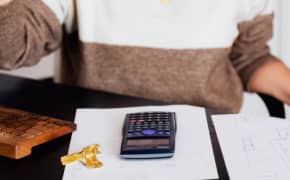 Frau am Schreibtisch. Hölzerne Tastatur, Papier und Taschenrechner auf dem Tisch.