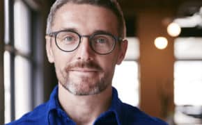 Mann mit Brille lächelt.