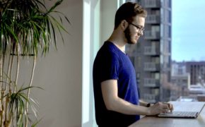 Mann vor Fenster an Laptop