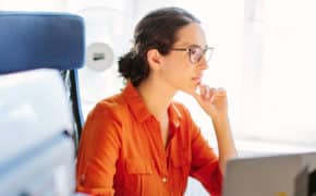 Frau mit Brille sitzt am Schreibtisch
