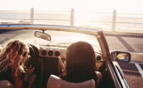 zwei Frauen sitzen in einem Cabrio am Wasser