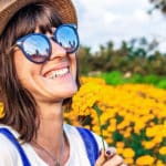 Frau steht mit Sonnenbrille in einem Blumenfeld