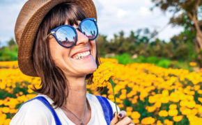 Frau steht mit Sonnenbrille in einem Blumenfeld
