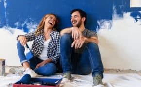 Mann und Frau sitzen vor einer halb bemalten Wand.