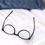 Schwarz umrandete Brille liegt auf Informationsblatt.