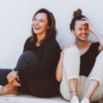 Zwei Frauen sitzen auf dem Boden und lachen
